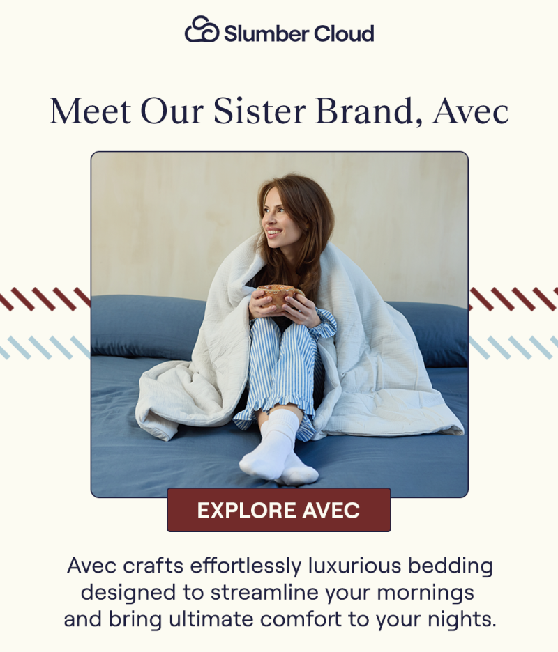 A woman wrapped up in a Mist Avec Cotton Quilt while sitting on a bed with the Harbor Align Sheet Set