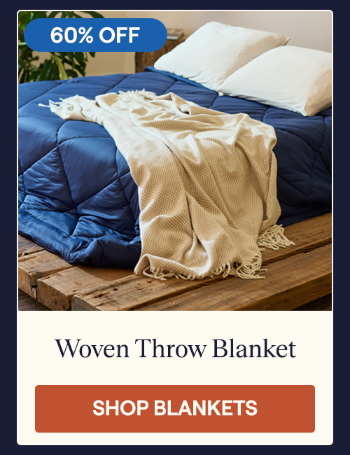 A bed with the Almond Woven Throw Blanket draping over the side
