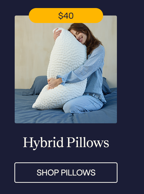 A woman sitting in bed hugging the Hybrid Pillow