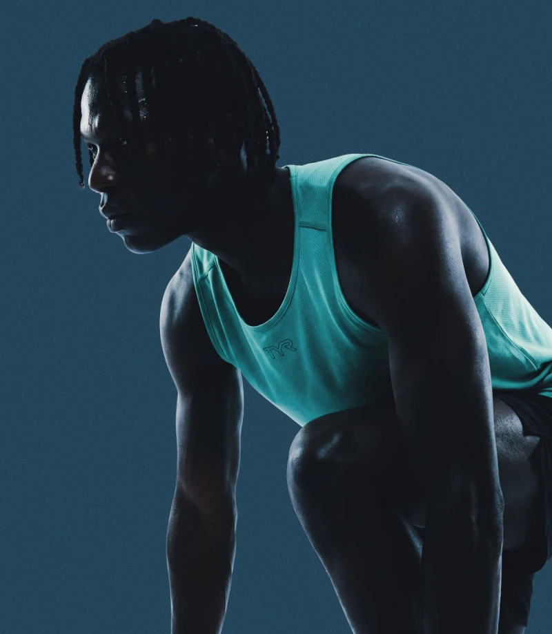 A person in a sleeveless athletic top crouching in a ready position.