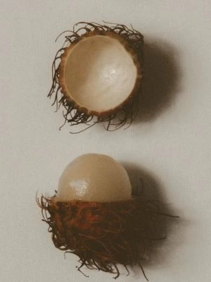 A peeled rambutan beside its empty shell