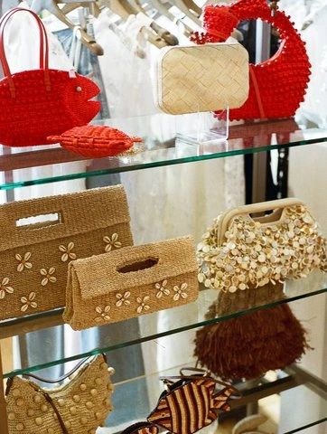 Straw bags and a red fish bag on glass showroom shelves