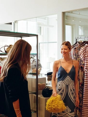 A yellow fringe bag held up in the showroom