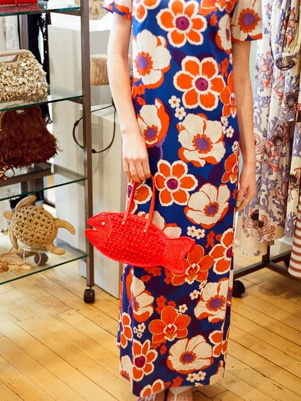 A model in a floral maxi dress carrying POOLSIDE's red fish bag in our New York showroom