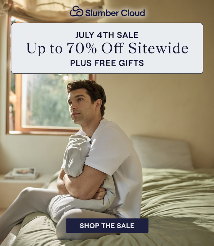 A man hugging a pillow while sitting on a bed